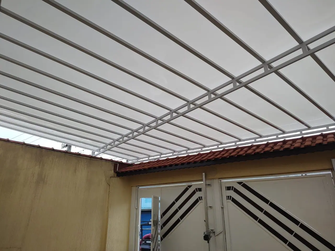 Cobertura fixa de policarbonato branco na entrada da casa em São Paulo