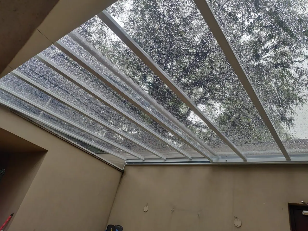 Cobertura retrátil transparente com estrutura branca em quintal em São Paulo
