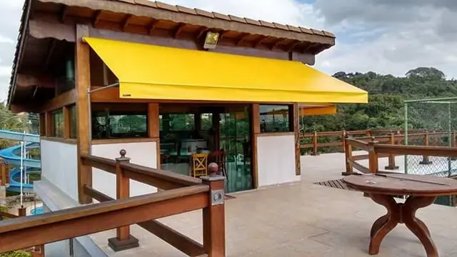 Toldo retrátil de braço articulado amarelo em área gourmet em São Paulo